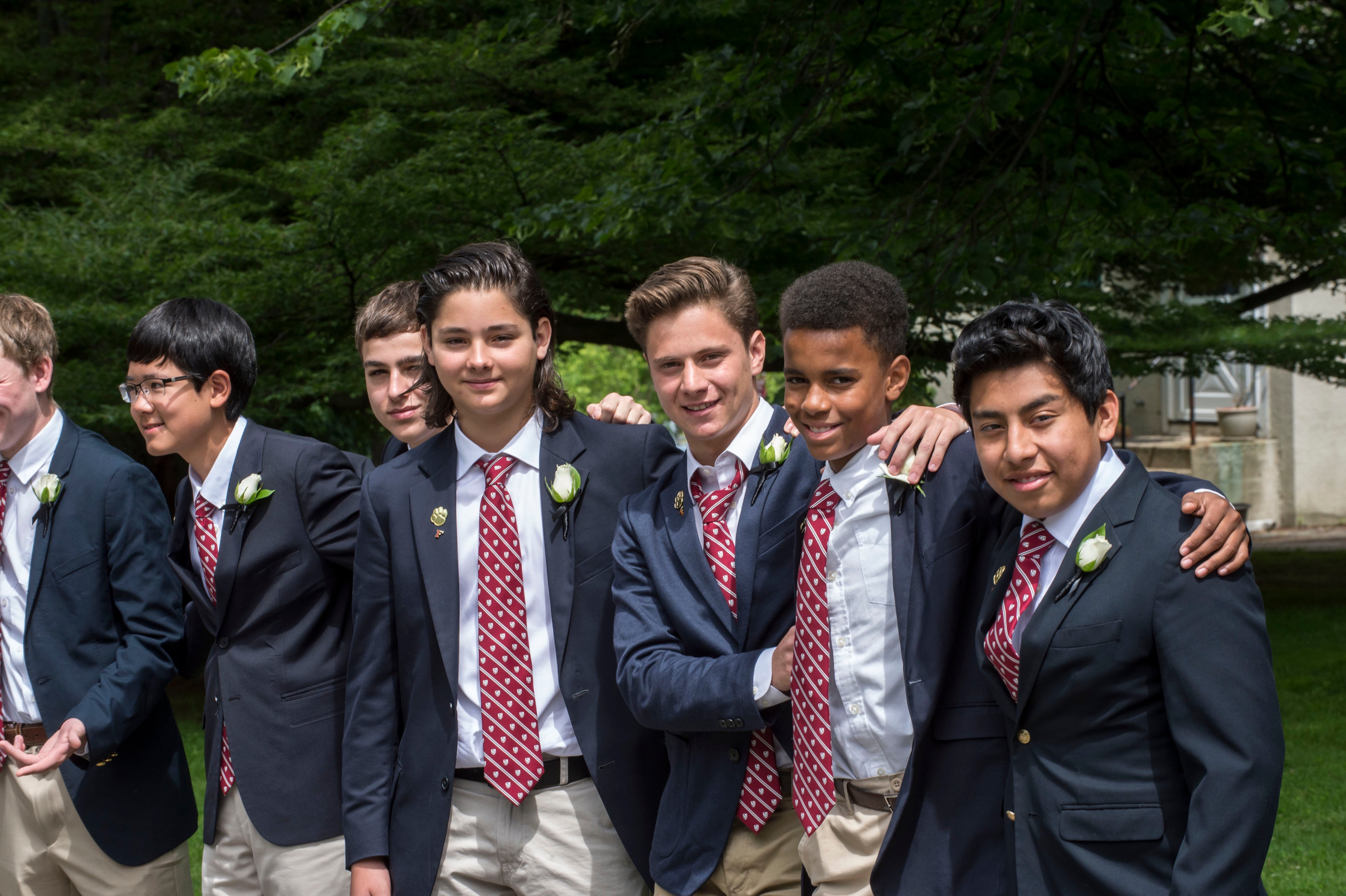 Seven students at The Fessenden School lined up together wearing the same suits.