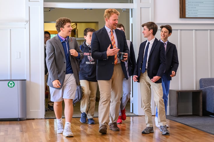A teacher walking and talking to five boarding school students at The Fessenden School in West Newton, MA.