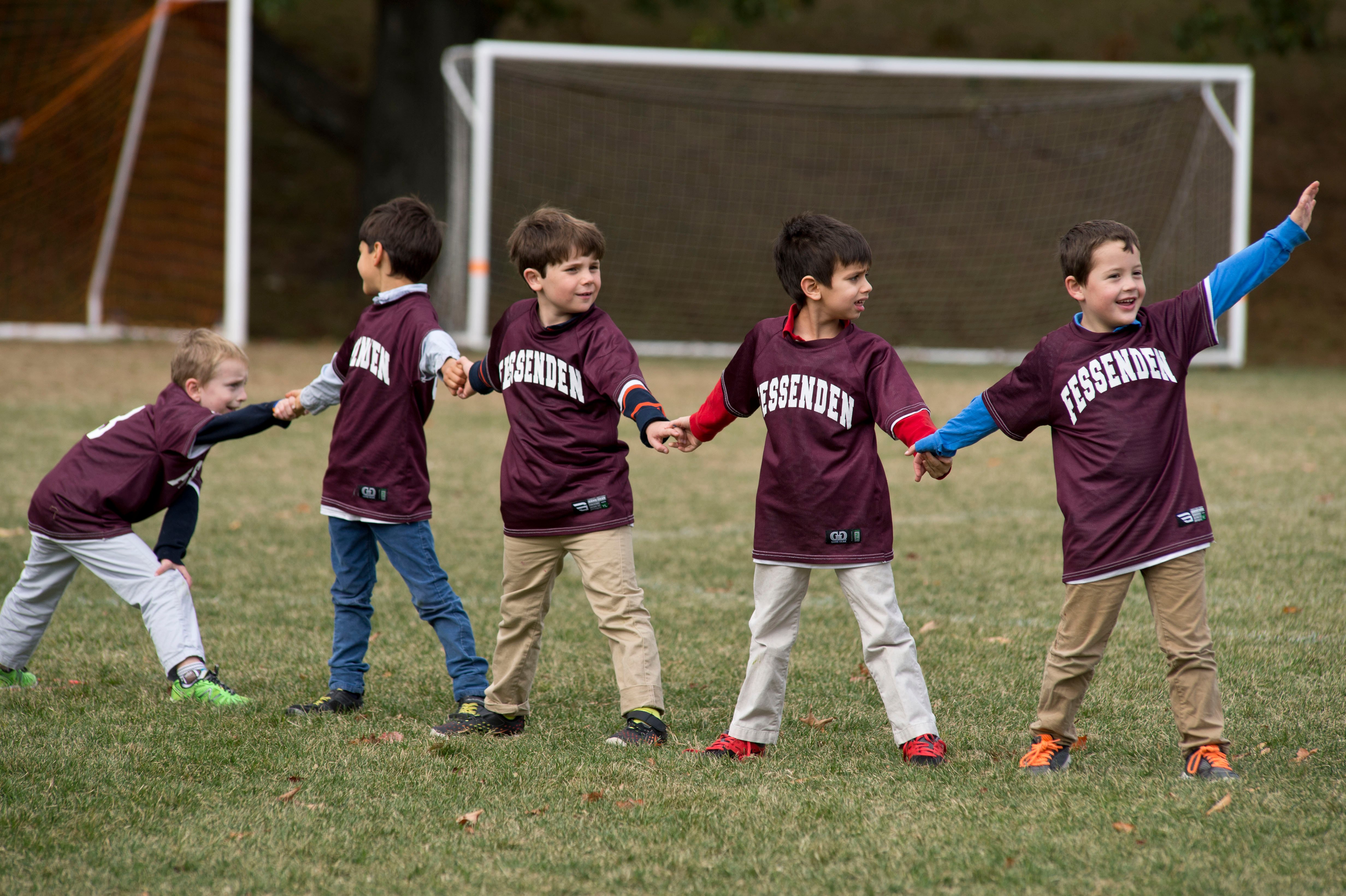 Five elementary school students at The Fessenden School playing on a field outside during class