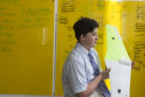 A junior boarding school student standing in front of a dry erase board at Fessenden’s Ciongoli Center for Innovation, showcasing a recent project he has been working on.
