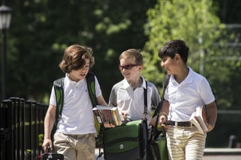 Three 12-year-old boys walking together through the campus of their junior boarding school.