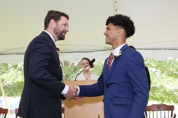 A Fessenden School student shaking hands with a teacher